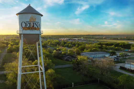 A water tower against a blue sky and overseeing the city