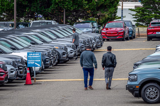 People look at cars at the dealeship.