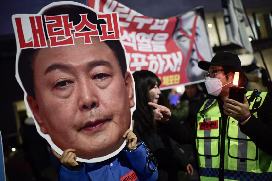 A protester holding a cardboard reading "leader of insurgents" on an image depicting the face of South Korea's President Yoon Suk Yeol takes part in a protest calling for his ouster outside the National Assembly in Seoul on Dec. 8, 2024.