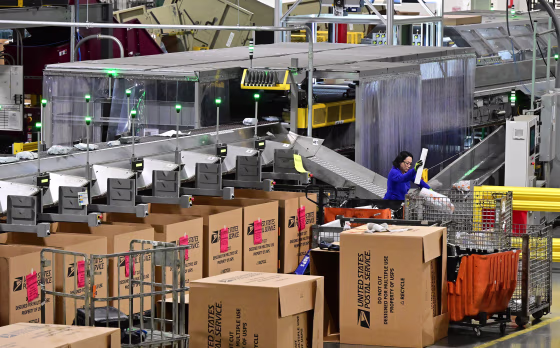 A postal workers sorts through mail and packages at the Los Angeles Processing and Distribution Center