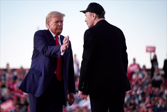 Donald Trump, left, leans in to pat Elon Musk's shoulder outside on stage during a rally