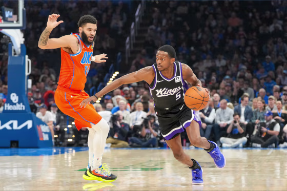 Sacramento Kings guard De'Aaron Fox, right, drives past Oklahoma City Thunder forward Kenrich Williams, left, during the first half of an NBA basketball game on Saturday.
