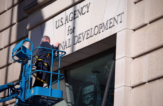 A worker removes the U.S. Agency for International Development sign on their headquarters on Feb. 7, 2025 in Washington.