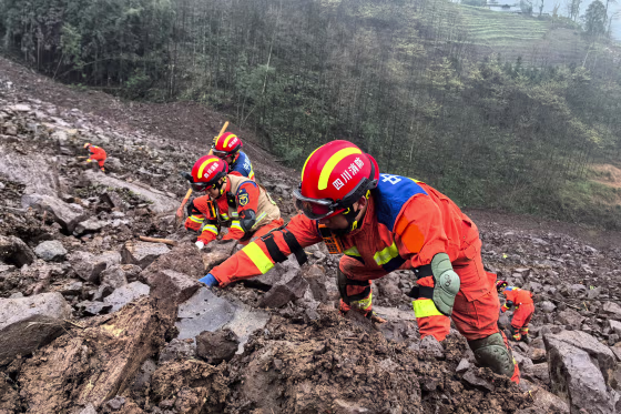 Rescuers search in debris outside on a hill
