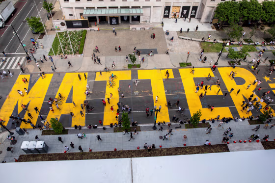 People walk down a street with the word "Matter" painted on it in bright yellow