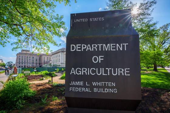 The sun flares over the top of the sign marking the headquarters building for the US Department of Agriculture.