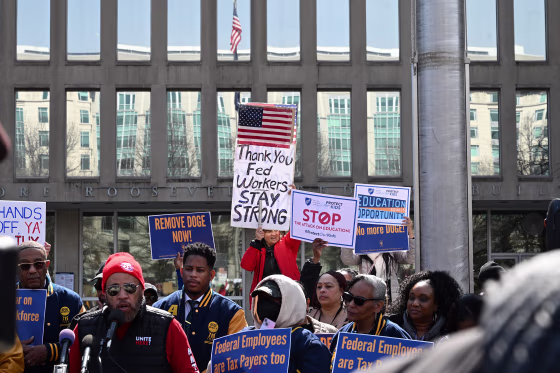 Protesters hold signs in solidarity with the American Federation of Government Employees of District 14
