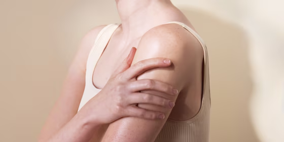 a photo of a woman wearing a white top touching her arm