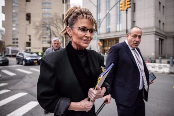 Sarah Palin walks outside carrying a notebook next to her lawyer