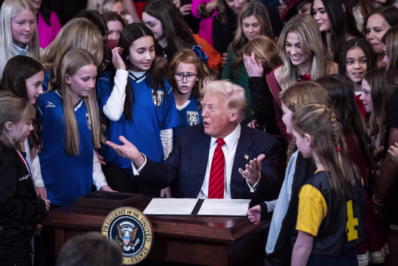 President Donald Trump is surrounded by girl athletes as he signs an executive order banning transgender athletes from participating in women's sports.