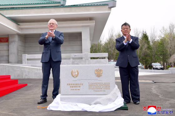 Two officials applauding at the ceremony for the construction of a bridge between North Korea and Russia