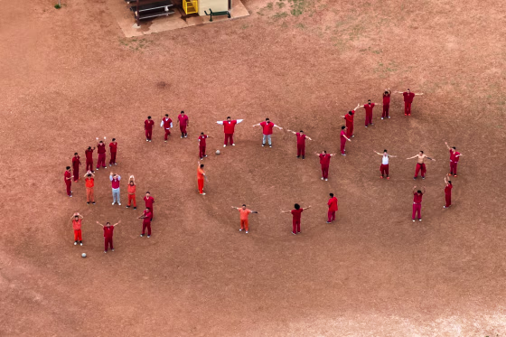 A drone view of detainees forming the letters SOS with their bodies in the courtyard