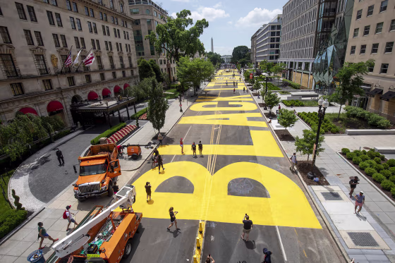 People walk down 16th street after volunteers, with permission from the city, painted "Black Lives Matter" on the street near the White House