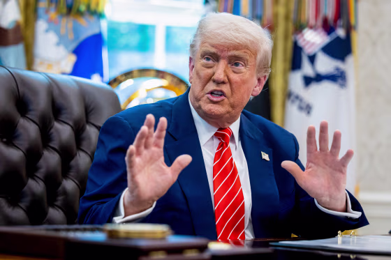 Donald Trump speaks while seated at his desk in the Oval Office
