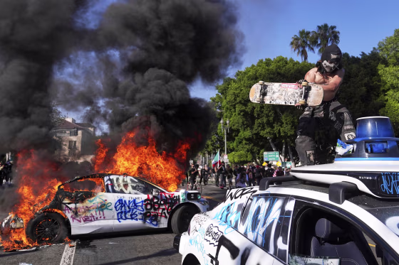 A Waymo taxi is vandalized while another burns