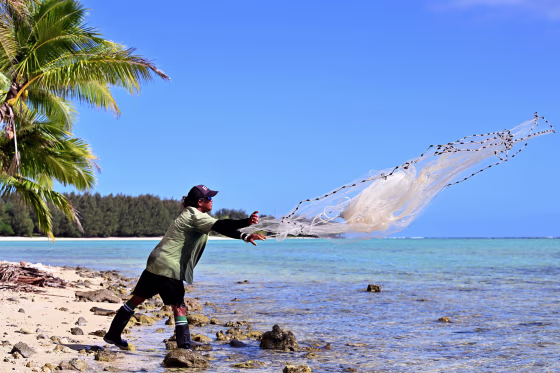 A fisherman casts his net into a lagoon 