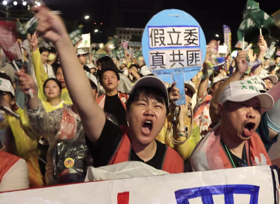 Image: People shout next to a sign reading ''Fake Legislators Are Real Communist Bandits'' during a campaign rally to promote recall vote targeting 24 Nationalist Party lawmakers in Taipei, Taiwan.