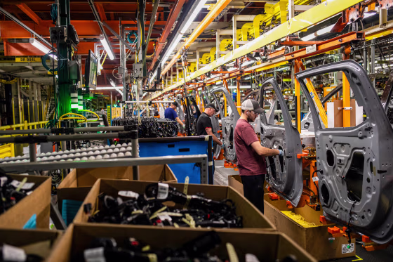 Workers assemble vehicle doors.