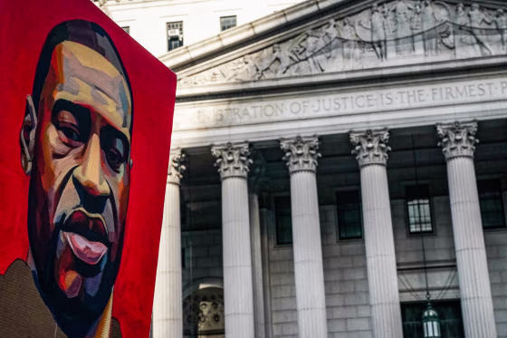 A poster of a painting of George Floyd is held up near a building exterior outside