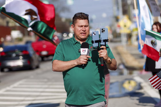 Mario Guevara holding a microphone and an iPhone via a tripod