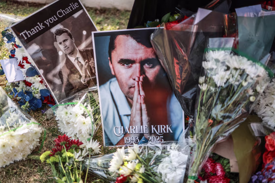 Pictures of Charlie Kirk next to bouquets of flowers on the grass