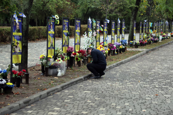 A man places a sign near the monuments with portraits and memorials of fallen Ukrainian Armed Forces on Oct. 1 in Odesa, Ukraine