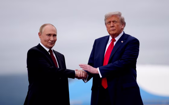 Putin, left, and Trump shake hands while standing outside