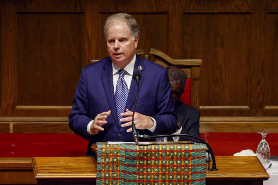 Former U.S. Sen. Doug Jones speaking in front of microphone.