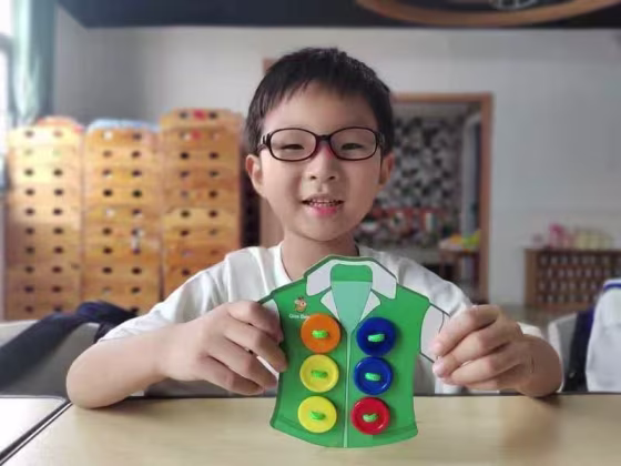 Yuanxin Zheng holding a paper craft t-shirt with buttons attached