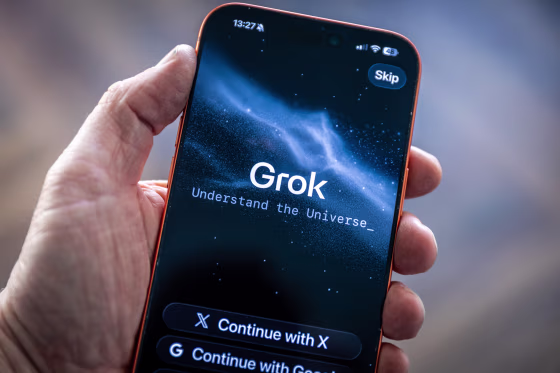 A hand holds a smartphone with the Grok app opened on the screen