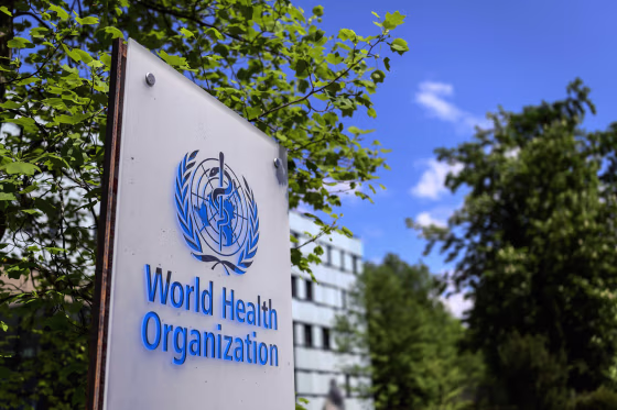 The blue World Health Organization logo is displayed on a sign outdoors.