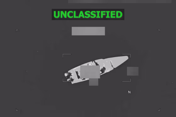 A black and white aerial view of a boat on the water, green text at the top reads "unclassified"