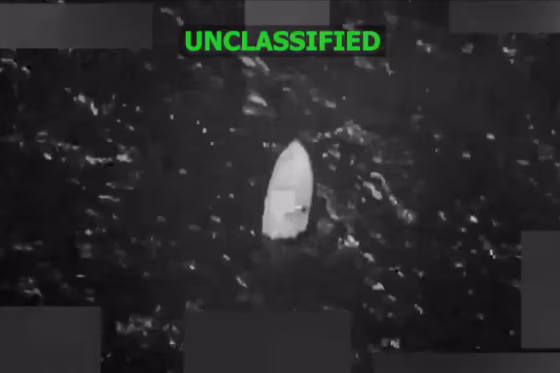 A grainy black-and-white still image taken from video shows a boat floating in the water.