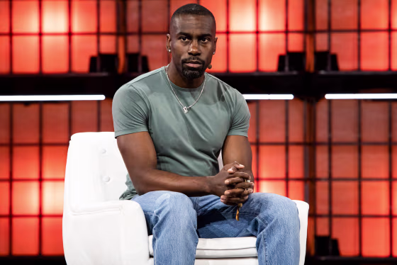 Deray Mckesson sits on a white couch on stage