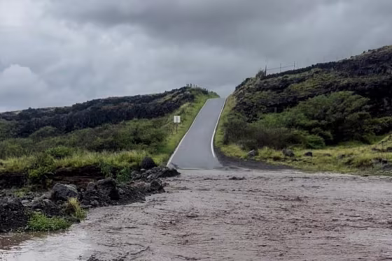 A view of flood waters in the front of a hilly road and grassy planes