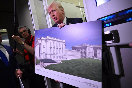 Donald Trump holds a rendering of the East Wing modernization as he speaks to reporters aboard Air Force One en route to Joint Base Andrews, Maryland, on March 29, 2026. 