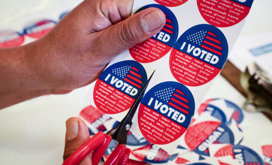 Close up on a sheet of "I Voted" stickers being cut on a table