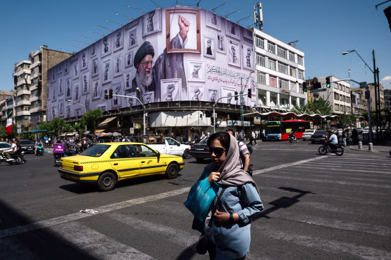 A woman walks near a billboard featuring an image of the late Supreme Leader of Iran, Ayatollah Ali Khamenei, in Tehran