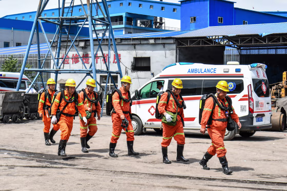 Rescue workers walk outside near an ambulance at the site of a coal mine explosion