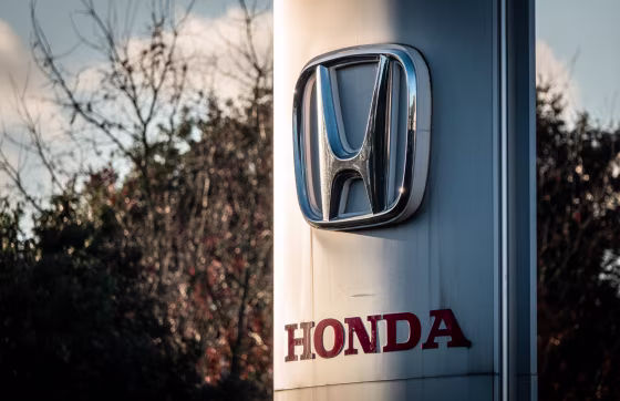 The logo of the Honda Motor Company is displayed outside a dealership 