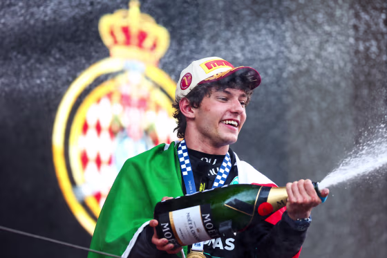 Andrea Kimi Antonelli pops a bottle of champagne on stage