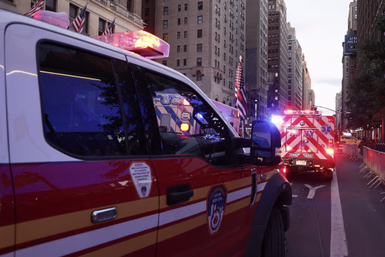 Fire Department vehicles with emergency lights flashing in Manhattan at dusk.