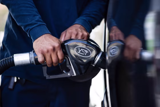 Close up of hands holding a gas pump inserted into a car