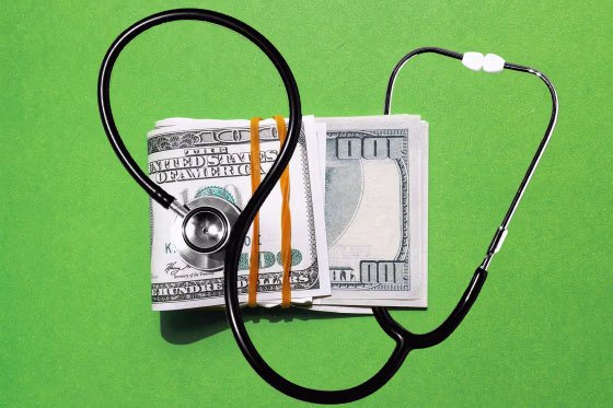 Photo illustration of stethoscope and a stack of one-hundred dollar bills 