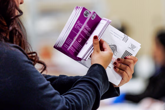 Vote by Mail ballots are inspected by a worker who flips through the envelope