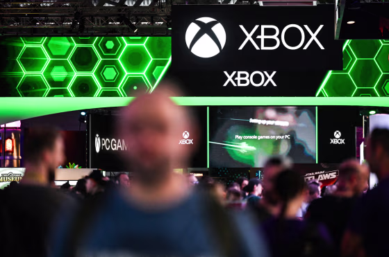 People walk around an exhibition floor, Xbobx signage is above them