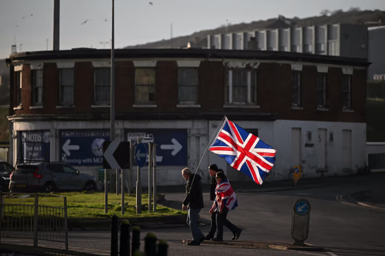 A group of people appears to be crossing the street while holding the Union Jack flag.