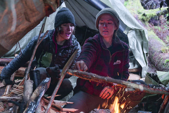 Amber Asay, left, and Jill Ashock light a fire outside while sitting underneath a tent