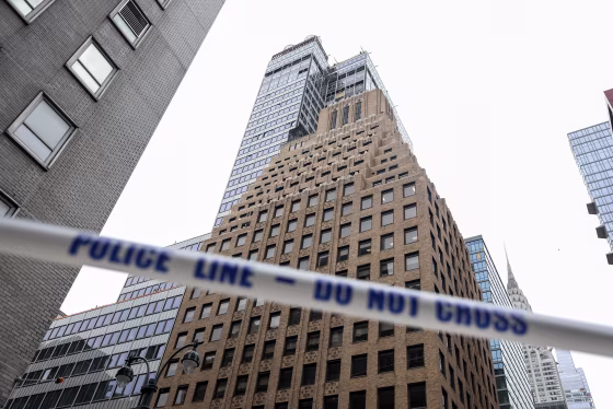 White tape with blue lettering reading POLICE LINE - DO NOT CROSS stretched in front of high-rise buildings in downtown Manhattan.
