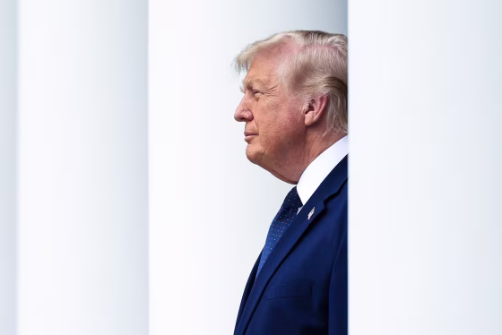 Donald Trump as seen from the side, standing in between white columns